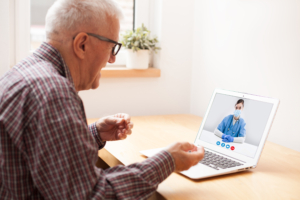 Elderly man talking to young UK female doctor via online telehealth video call